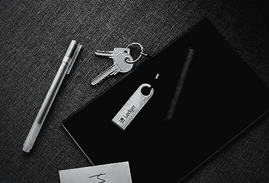 Ledger-Hardware-Wallet neben Schlüsselbund und Stift